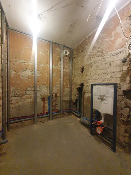 Darbu gaita: metāla karkass gar ķieģeļu sienām, jaunas ūdens caurules un pod instalācija.