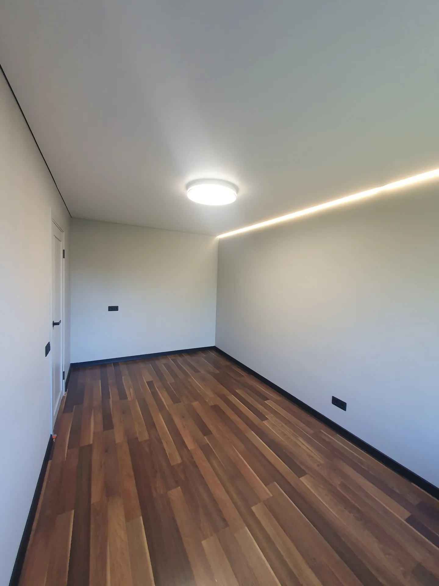 Натяжной потолок с LED-линией вдоль стены и настенный светильник.